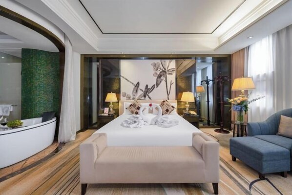 A hotel room with a bed, a sitting area, a reception desk, and a mirror. - Wuhan Meichen Yueshang Boutique Hotel (Wuhan)