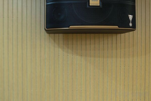 A wall-mounted speaker with a label, positioned against a textured wall. - Wuhan Meichen Yueshang Boutique Hotel (Wuhan)