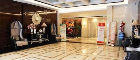 A hotel lobby with a geometric patterned floor, a reception desk, and a large chandelier.