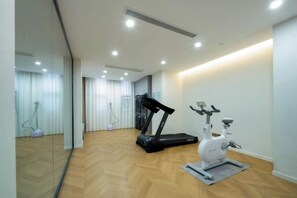 A modern gym with a treadmill and an exercise bike, wooden flooring, and a glass wall. - Wuhan Meichen Yueshang Boutique Hotel (Wuhan)