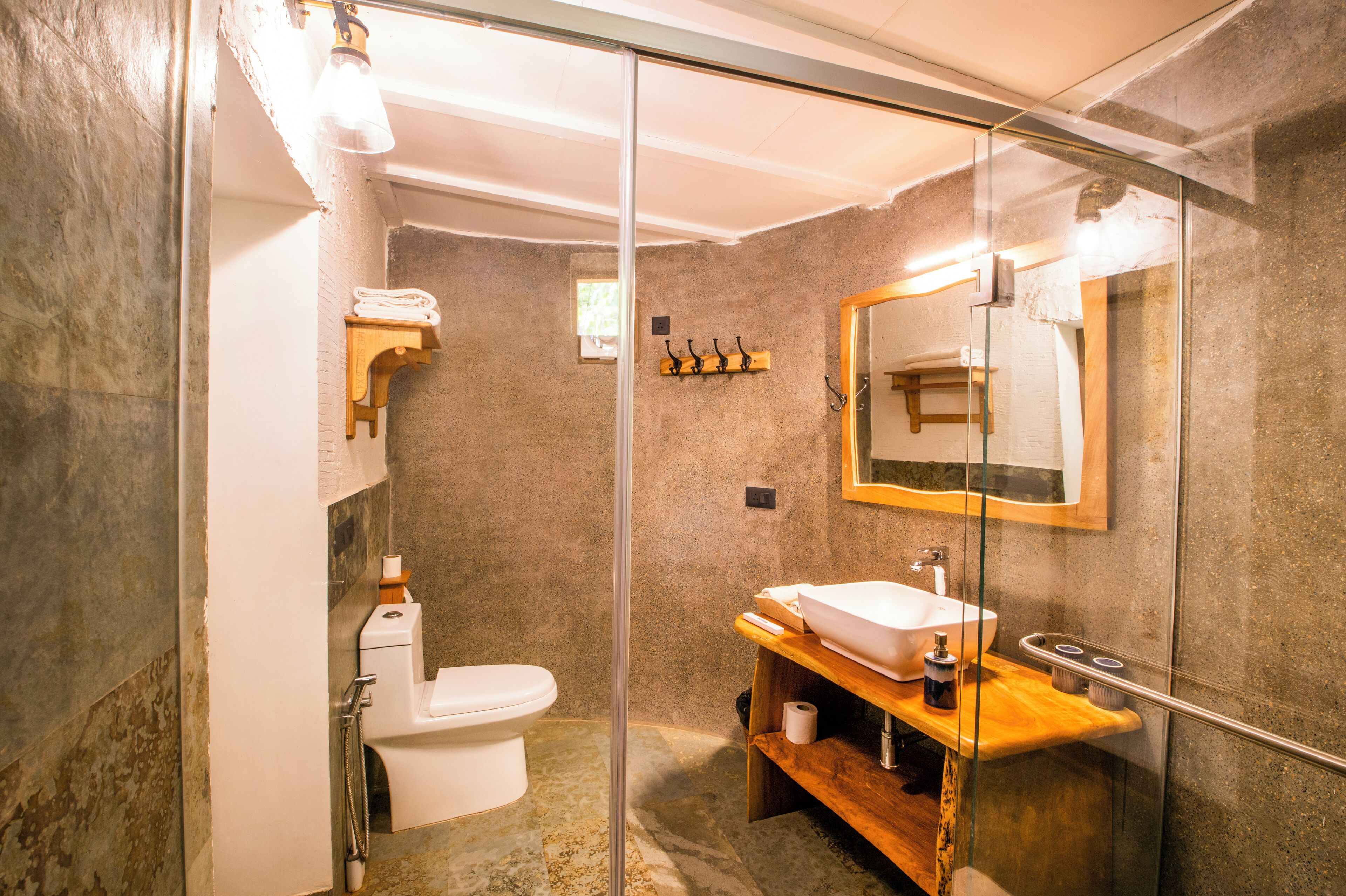 Un bagno moderno con box doccia in vetro, un water bianco, un mobile bagno in legno con lavandino e uno specchio sopra il mobile.