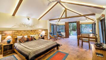A spacious bedroom with a large bed, two chairs, a desk, and a view of the outdoors.