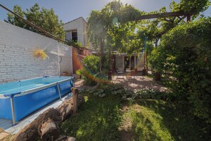 A backyard with a swimming pool, a brick wall, and a wooden deck. - Casa Jade: A Bright and Cozy Home with a Garden (Godoy Cruz)