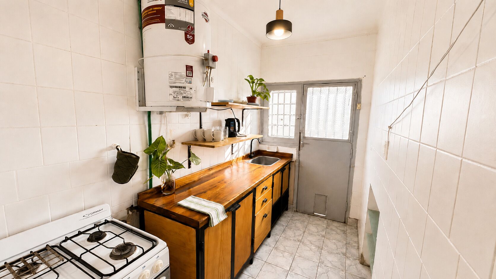 Cocina compacta con estufa a gas, encimera de madera y calentador de agua.