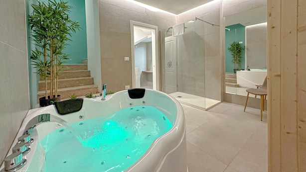 A modern bathroom with a bathtub, a glass shower enclosure, and a staircase leading to an upper level.