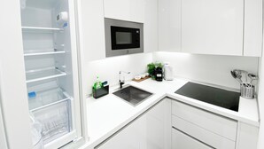 Une cuisine moderne avec des meubles blancs, un four à micro-ondes encastré, un évier et une machine à café.