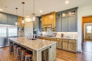 Una cocina con una isla grande, taburetes de bar y armarios de madera.