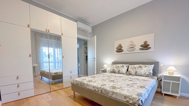 A bedroom with a bed, bedside tables, a wardrobe, and a mirror. - Torre 24 - Luxury Naviglio suite (Milano)