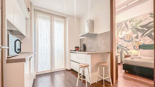 A compact, modern room with a kitchenette, a dining area, and a bed.