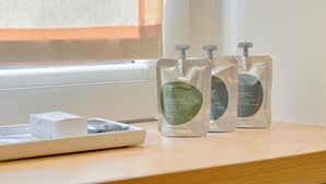 Tres botellas de gel de ducha sobre una superficie de madera cerca de una ventana.