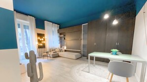Un salon moderne avec un mur d’accent bleu, un canapé blanc, une table à manger et un cactus.