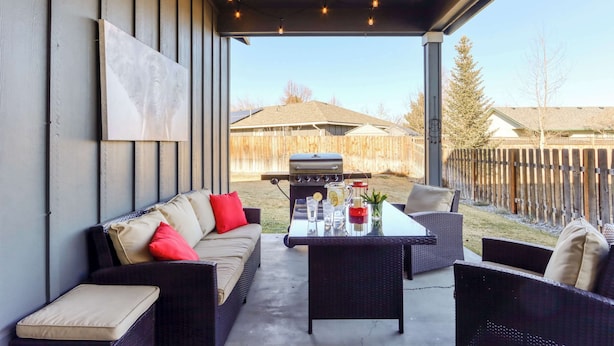 Une terrasse extérieure avec un canapé, des chaises, une table et un barbecue.