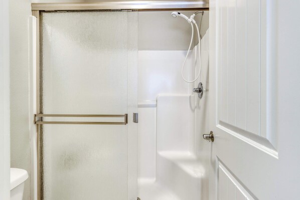 A bathroom with a shower, a toilet, and a door with a handle. - Bends Artful Adventure 4 BDR (Bend)