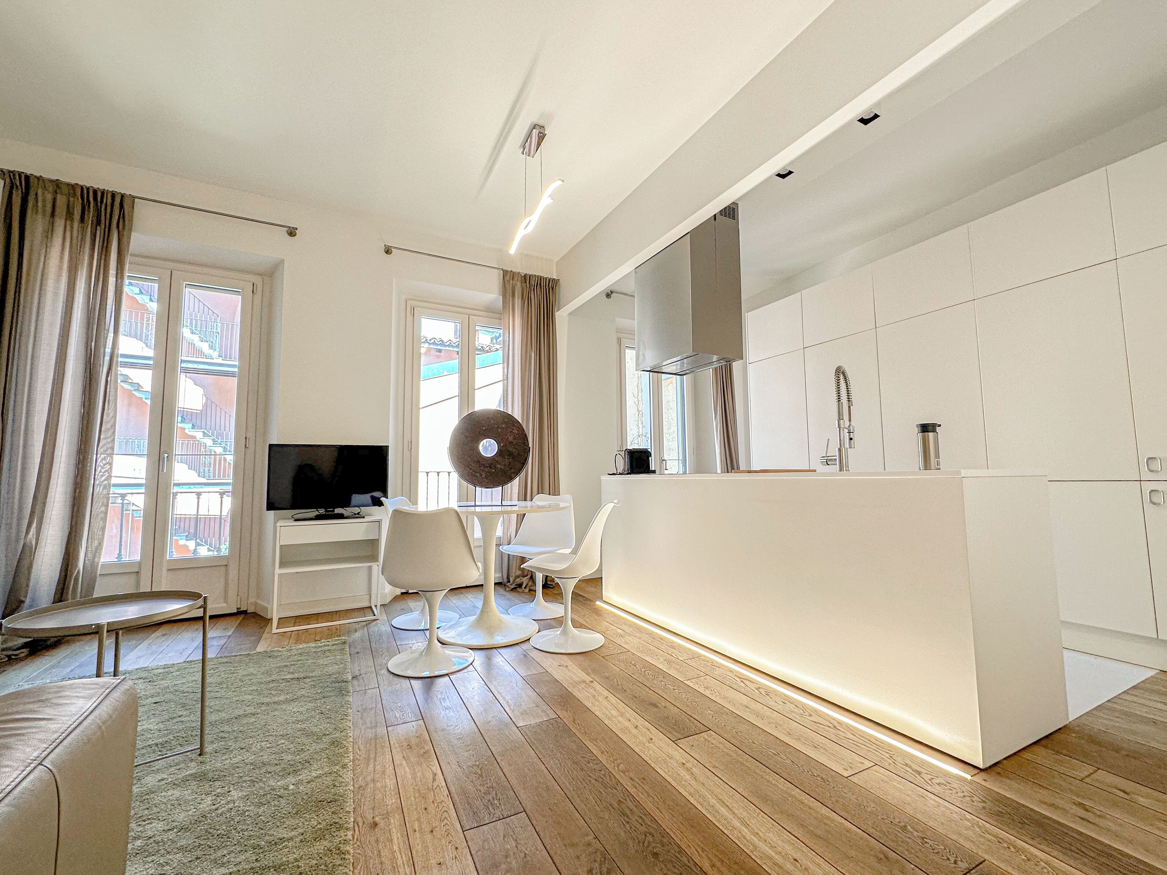A modern kitchen with white cabinetry, a built-in oven, and a stainless steel sink.