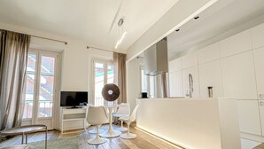 Une cuisine moderne avec des meubles blancs, un four encastré et un évier en acier inoxydable.