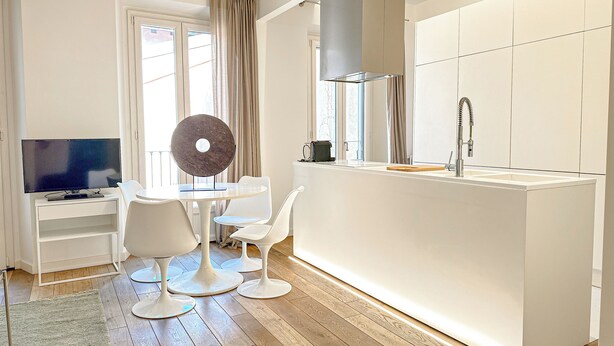 Une cuisine moderne dotée d’un îlot central, de meubles blancs et d’un four encastré.