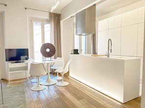 Een moderne keuken met een centraal eiland, witte keukenkastjes en een inbouwoven.