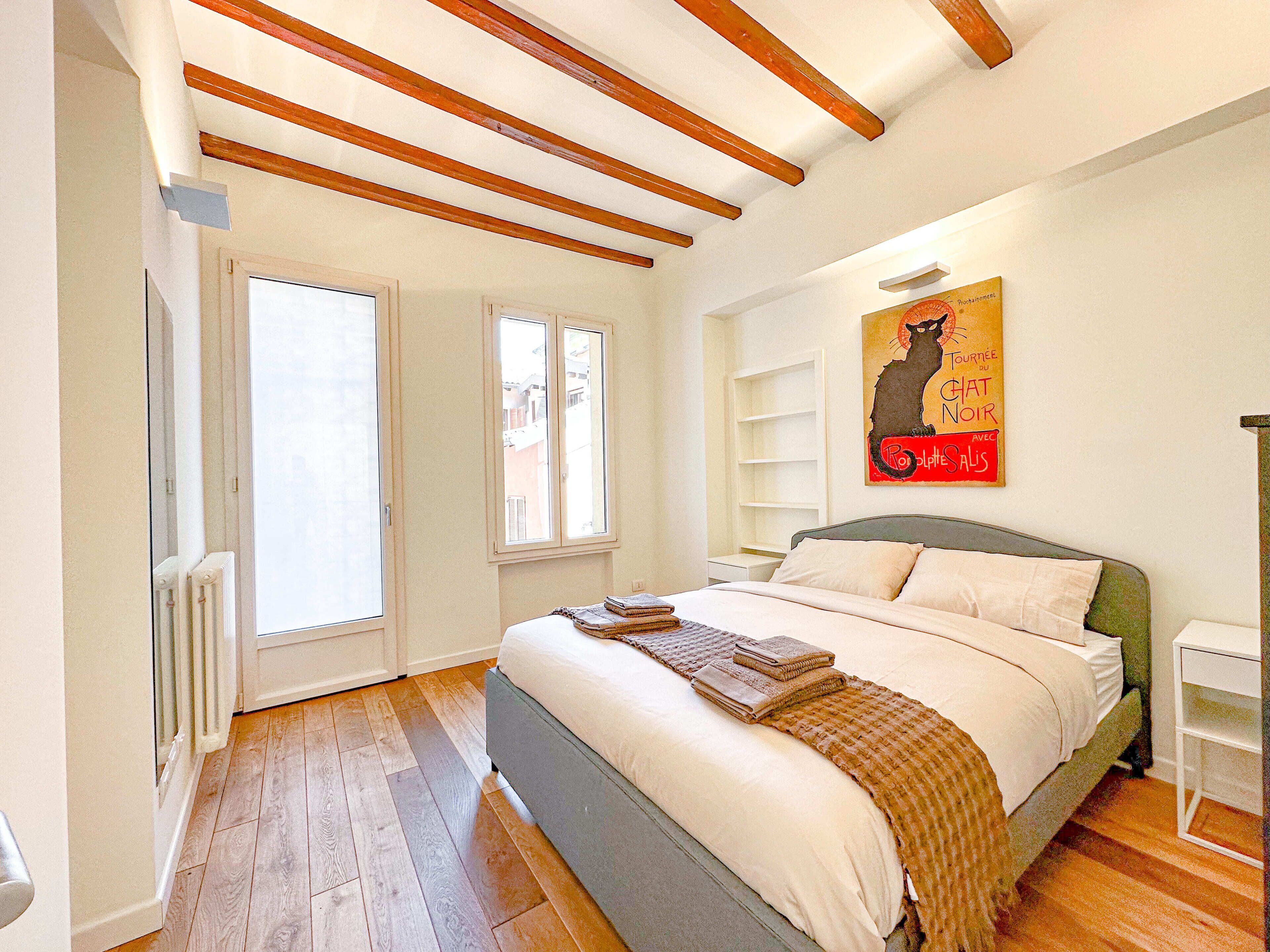 A bedroom with a bed, a radiator, a window, and a painting on the wall.