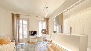 Un salon moderne comprenant un canapé, un téléviseur et un coin repas avec une table et des chaises.