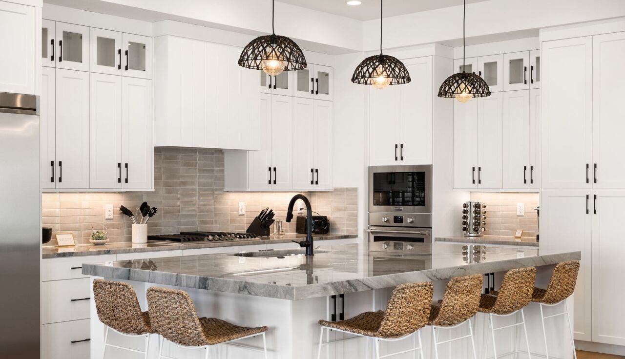 A modern kitchen with white cabinetry, a central island with bar stools, and pendant lighting.