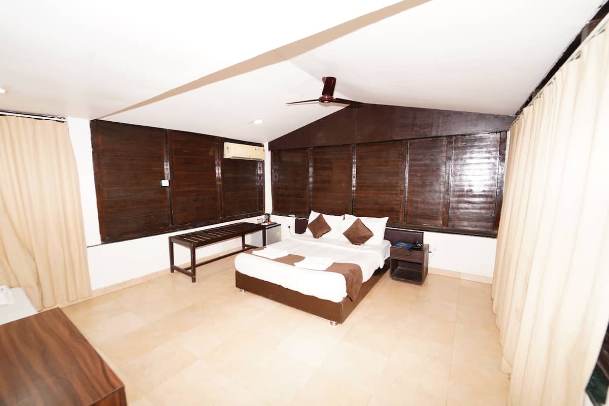 Une chambre à coucher avec un lit, des tables de chevet, un ventilateur de plafond et une fenêtre avec des rideaux.