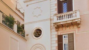 Een meerlaags gebouw met een gevel van steen, een balkon met een balustrade en een klein rond raam.