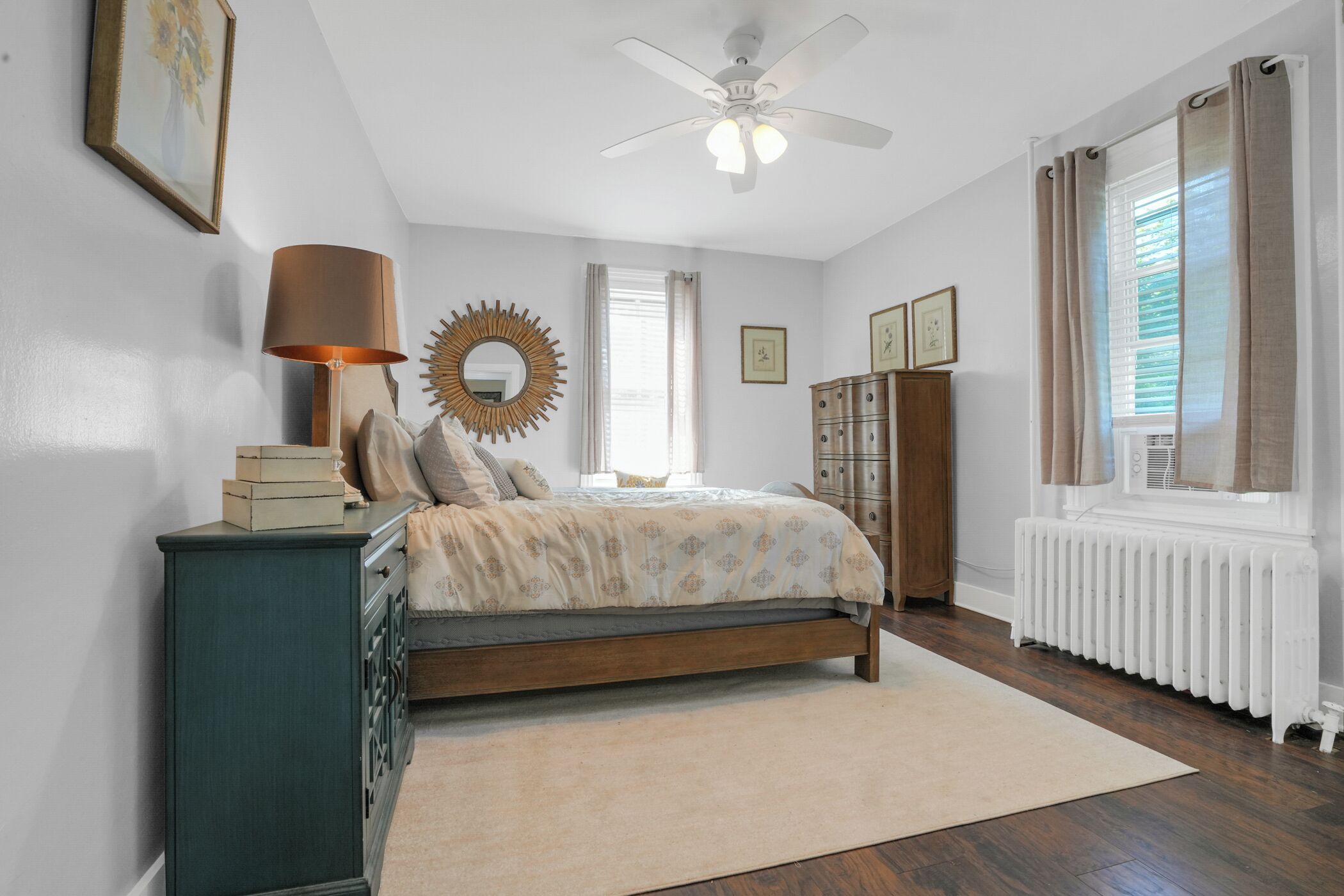 A bedroom with a bed, dresser, and a ceiling fan.
