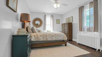 A bedroom with a bed, dresser, and a ceiling fan.