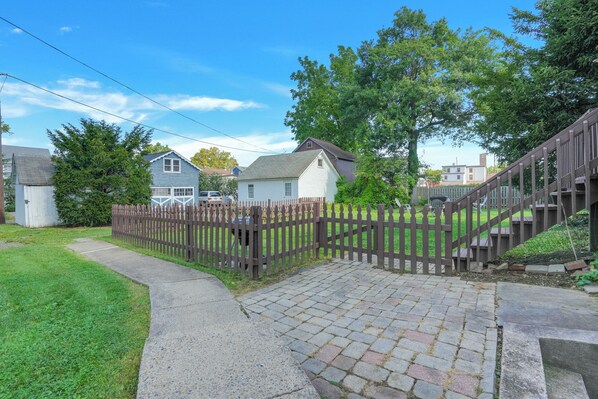 A residential property with a paved driveway, a wooden fence, and a staircase leading to a deck.