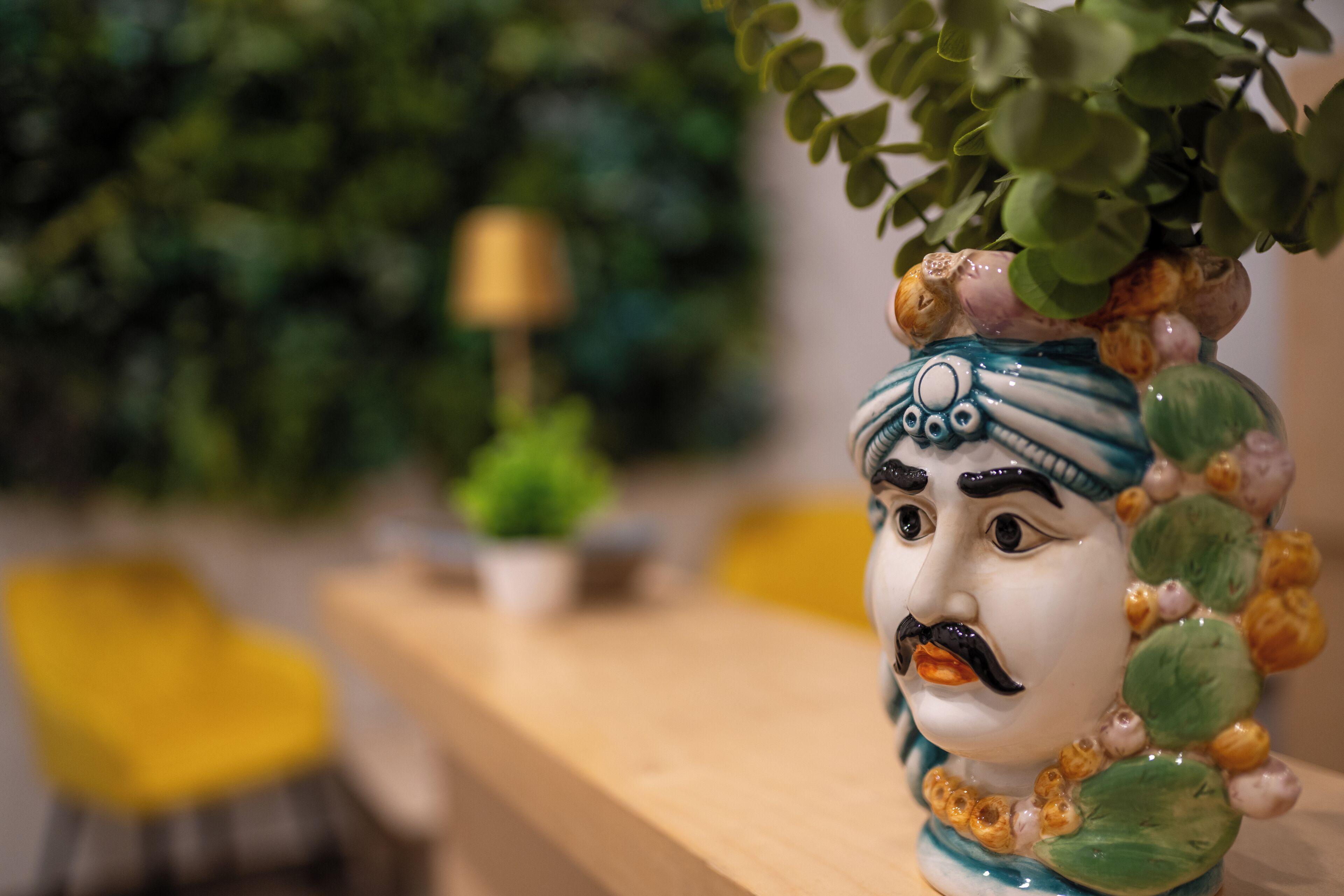 Un jarrón de cerámica con una figura decorativa en una superficie de madera.