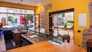 A modern café with a glass partition, wooden tables, and a brick accent wall. - Suebi Central - Deluxe Rooms & Family Suites (Termoli)
