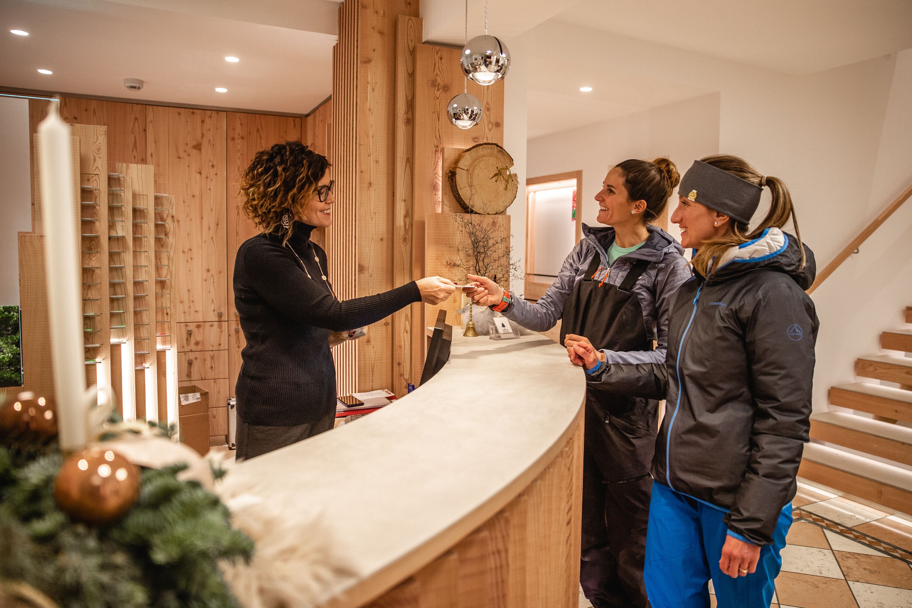 A reception area with a wooden counter, a Christmas tree, and a staircase in the background.