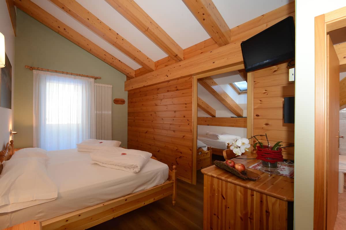 A wooden cabin with a bed, a small table with a plant, and a bathroom with a shower.