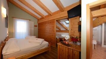 A wooden cabin with a bed, a small table with a plant, and a bathroom with a shower.
