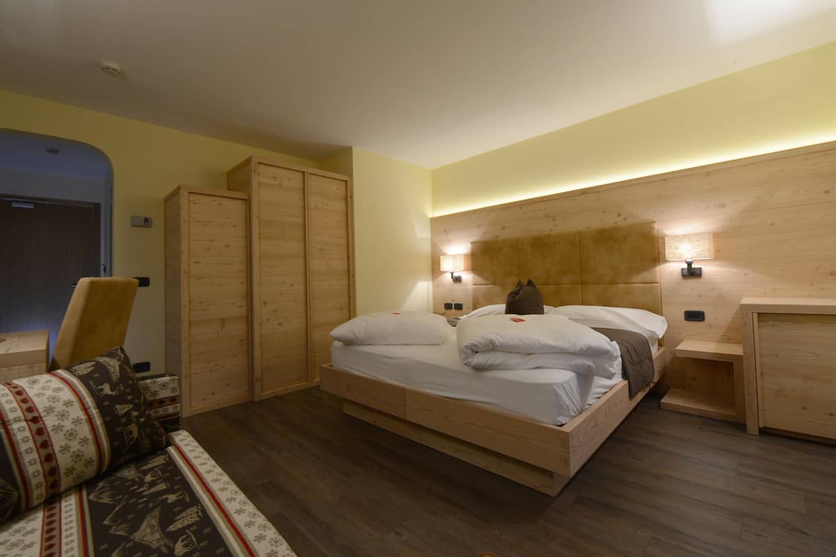 A bedroom with a wooden bed, a wardrobe, a chair, and a bedside table.