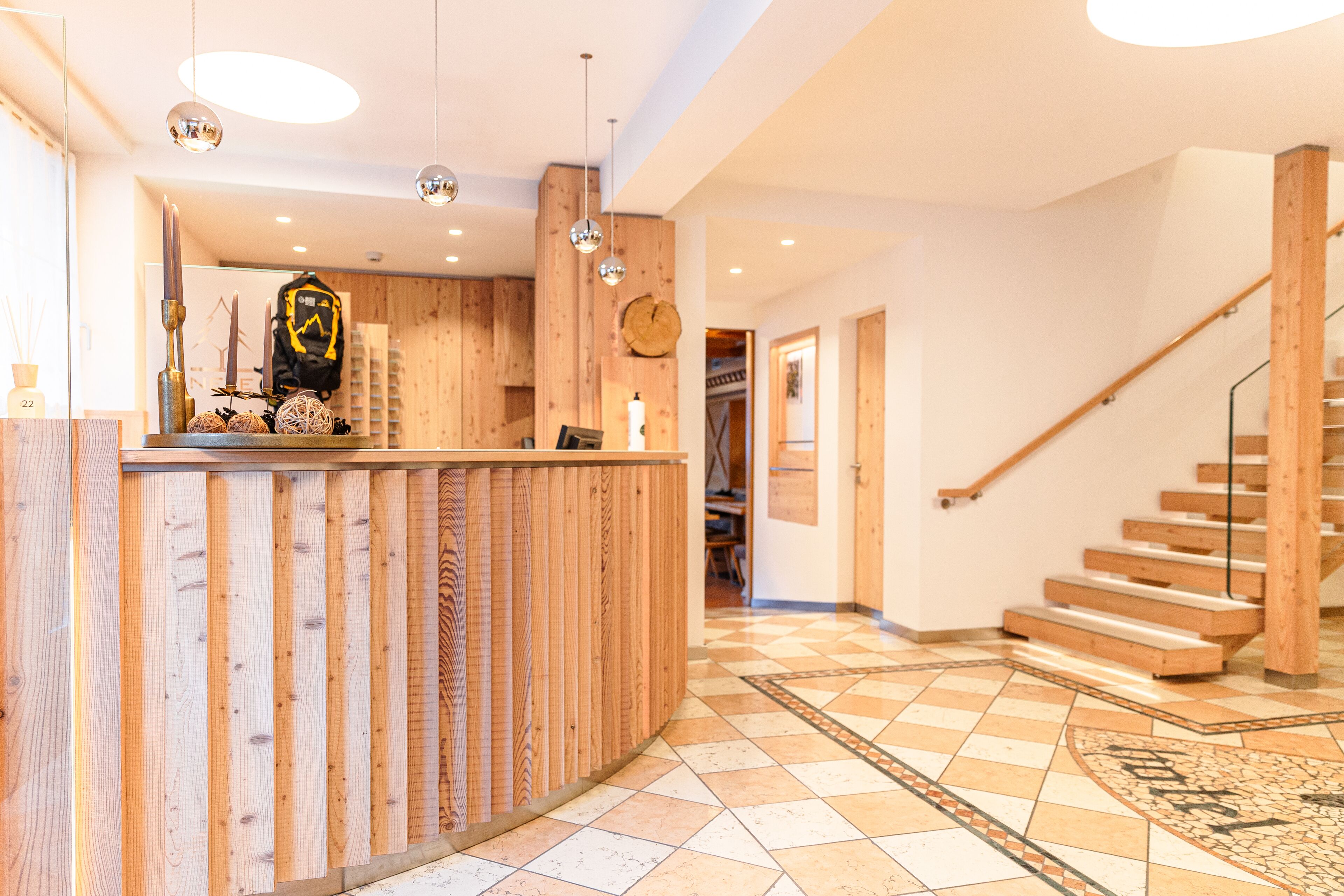 Un espace d’accueil avec un comptoir en bois, un escalier et un sol carrelé.