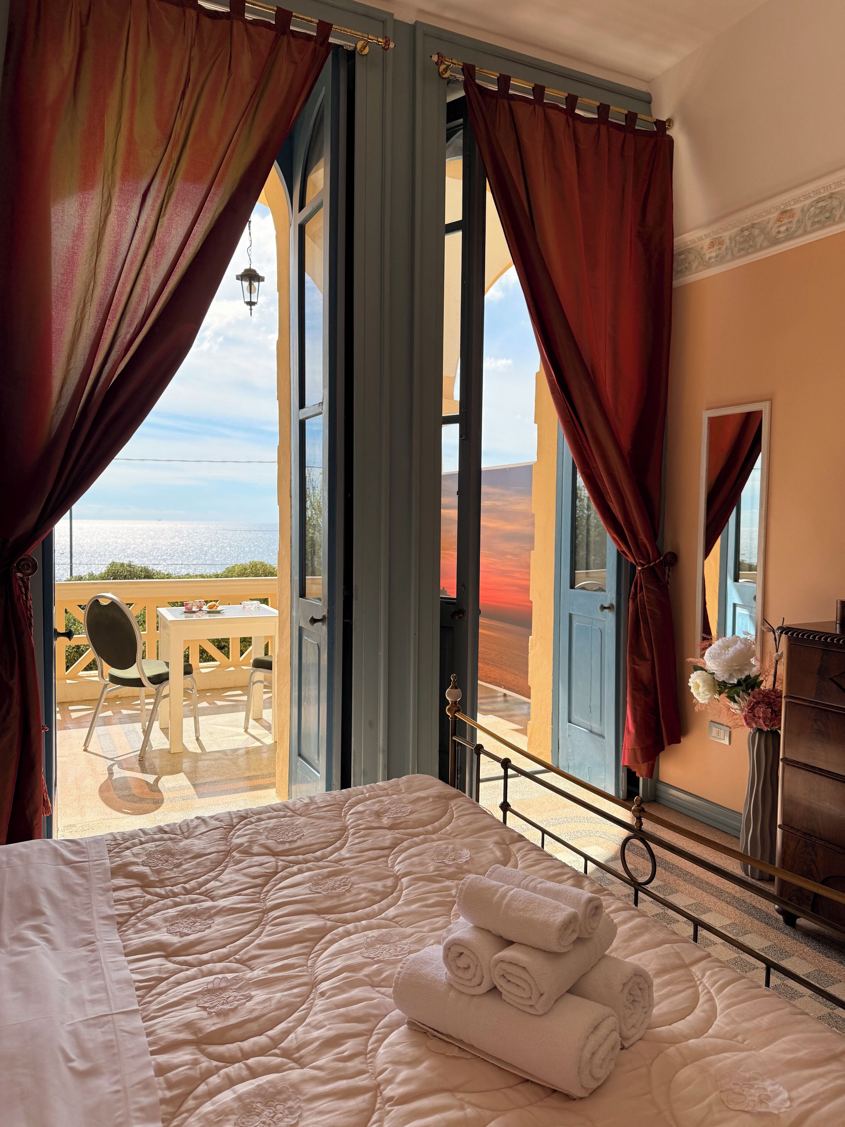 Un dormitorio con cama, vistas al mar y un balcón con mesa y sillas.