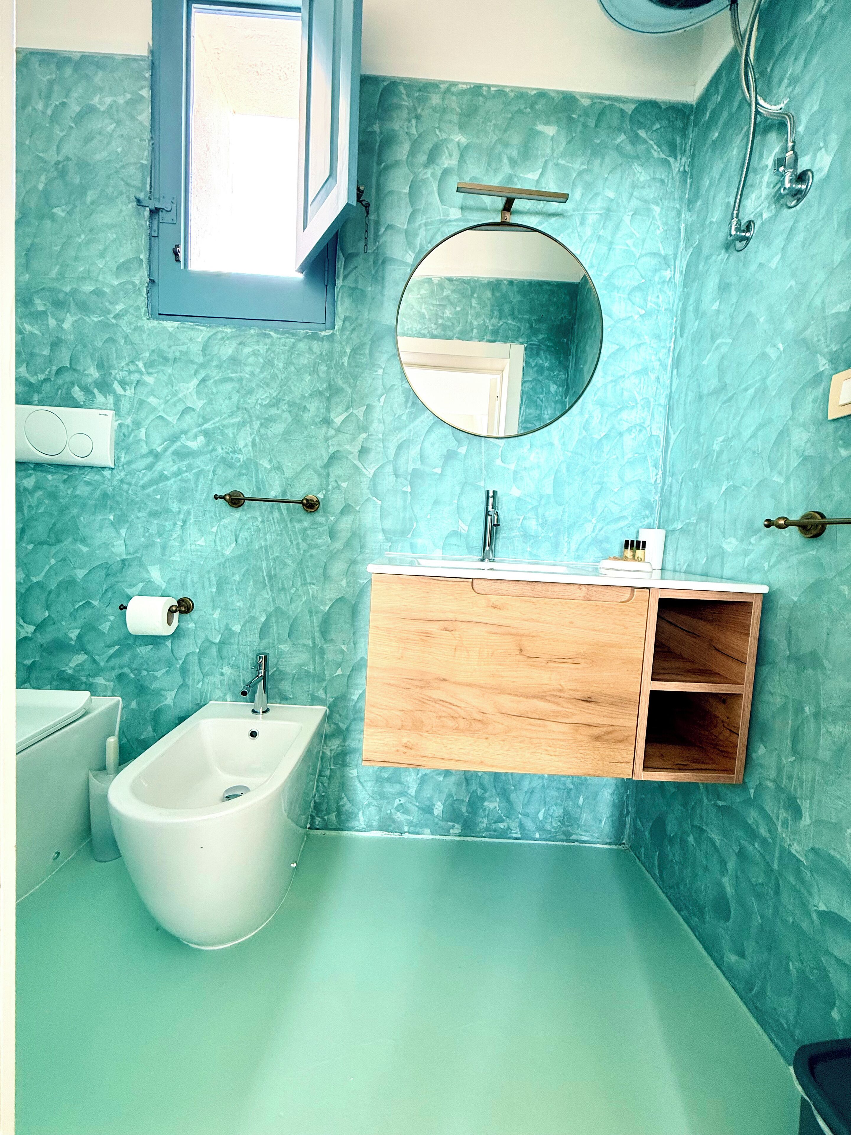 A bathroom with a bidet, a sink with a wooden vanity, a mirror, and a towel rack.