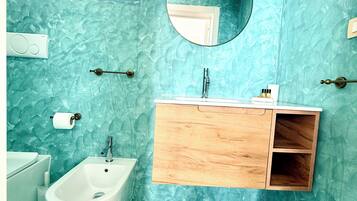 A bathroom with a bidet, a sink with a wooden vanity, a mirror, and a towel rack.