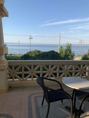 Enjoy the serene sea views from this balcony, featuring a geometric-patterned railing, two comfortable chairs, and a small table.