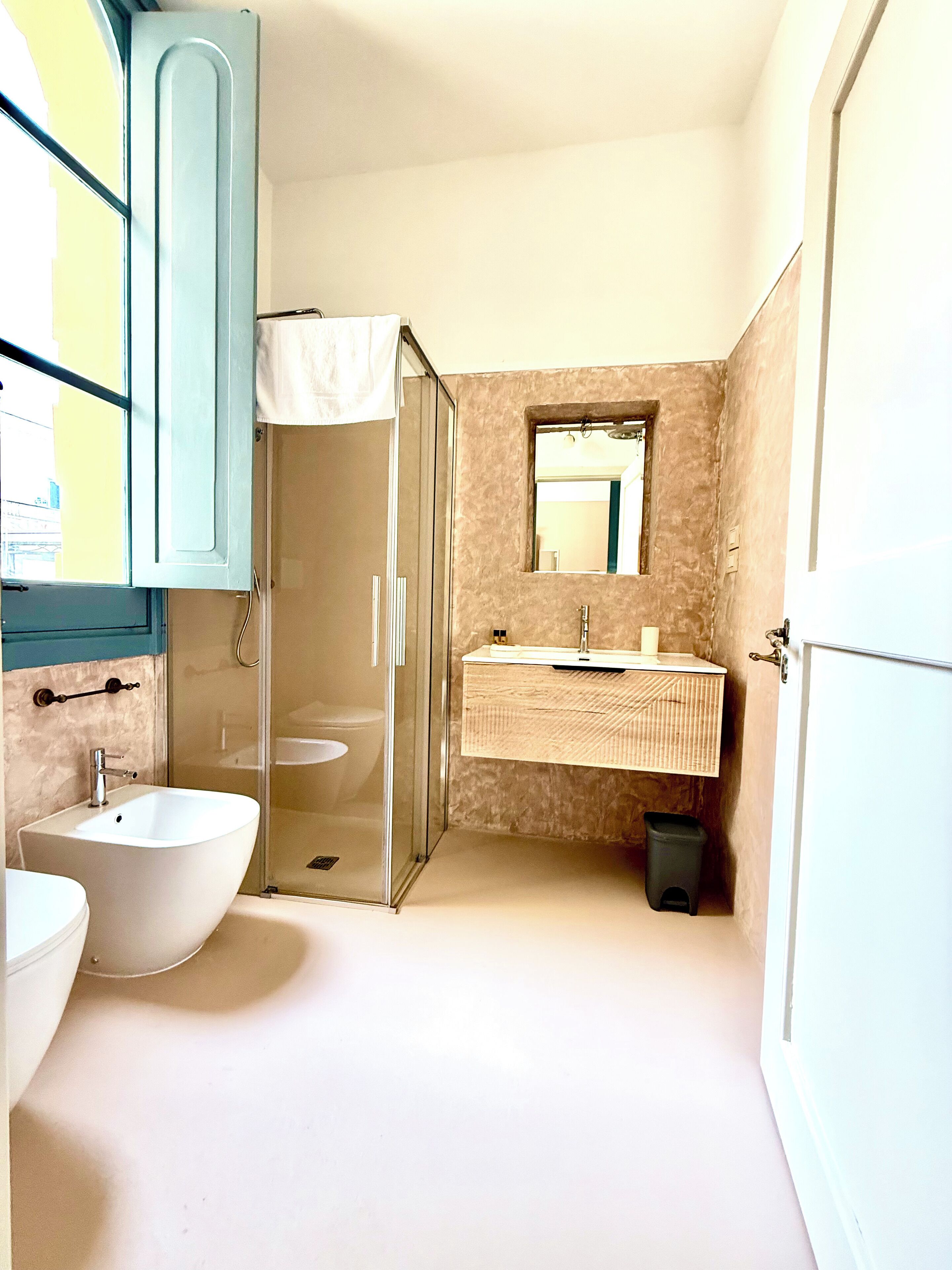 A bathroom with a glass-enclosed shower, a white sink, and a mirror above the sink.