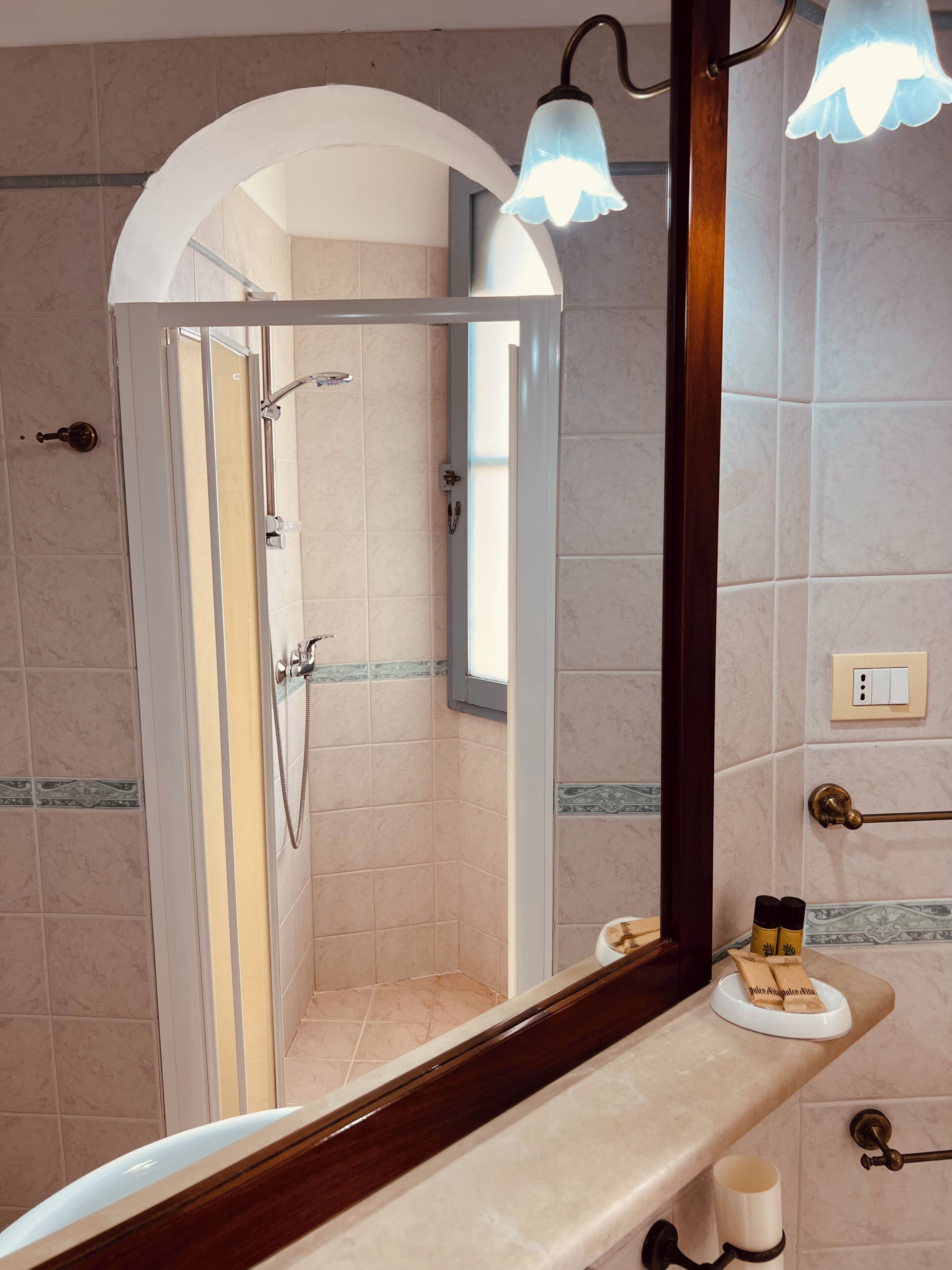 A bathroom with a shower, a vanity with a mirror, and a towel rack.