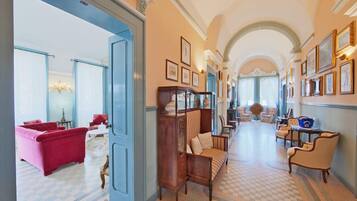 A hallway with a checkered floor, a red armchair, a wooden cabinet, and a blue door.