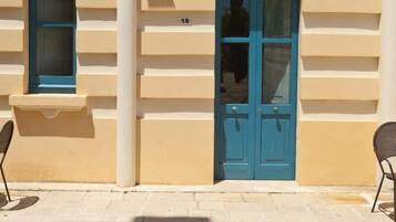 Un edificio con fachada color crema, dos puertas azules y una ventana pequeña con marco azul.