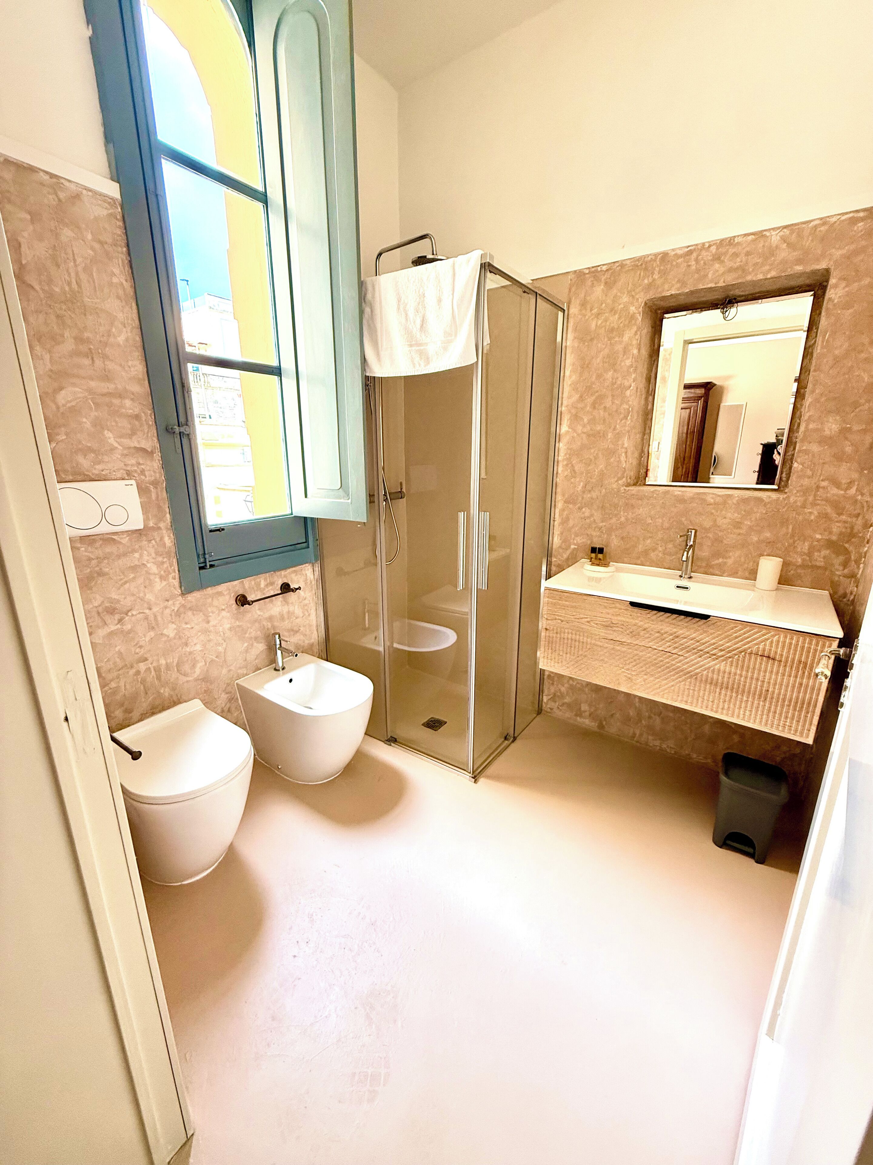 A modern bathroom with a glass-enclosed shower, two sinks, and a toilet.
