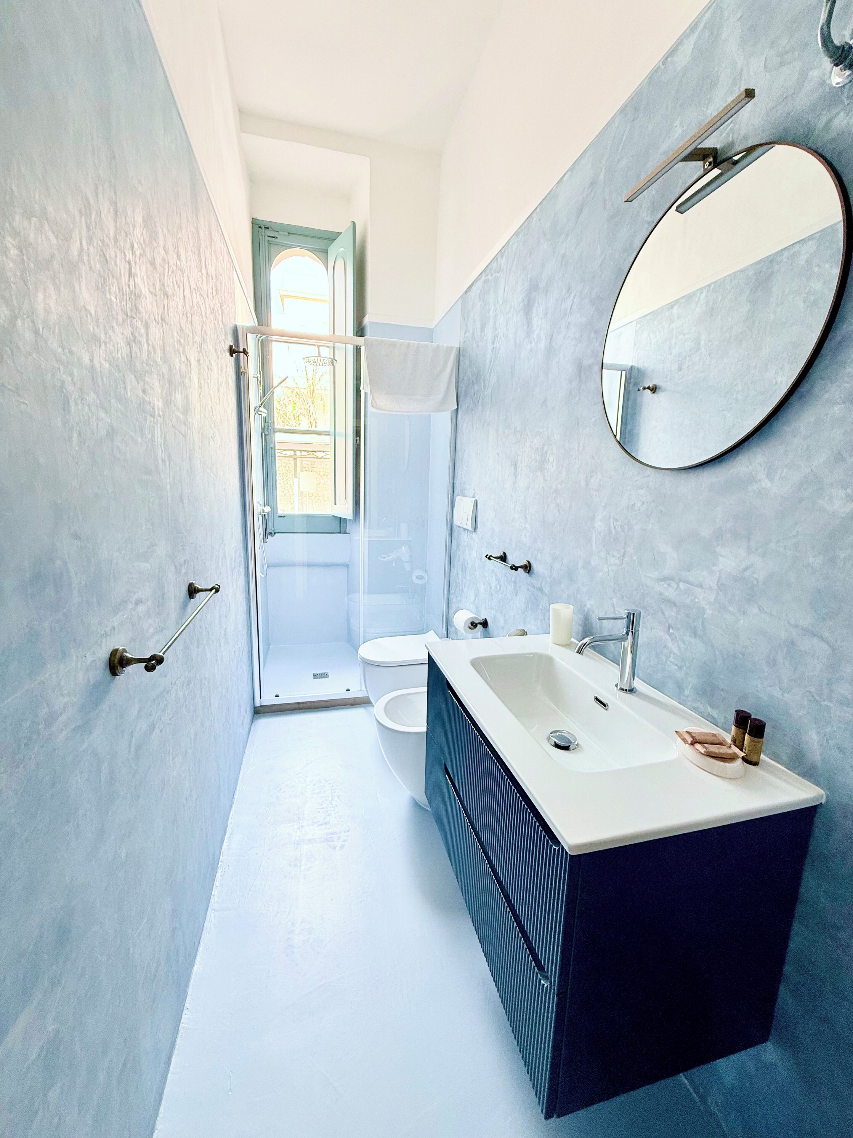 Un baño moderno con cabina de ducha, inodoro, lavamanos con tocador y un espejo grande.