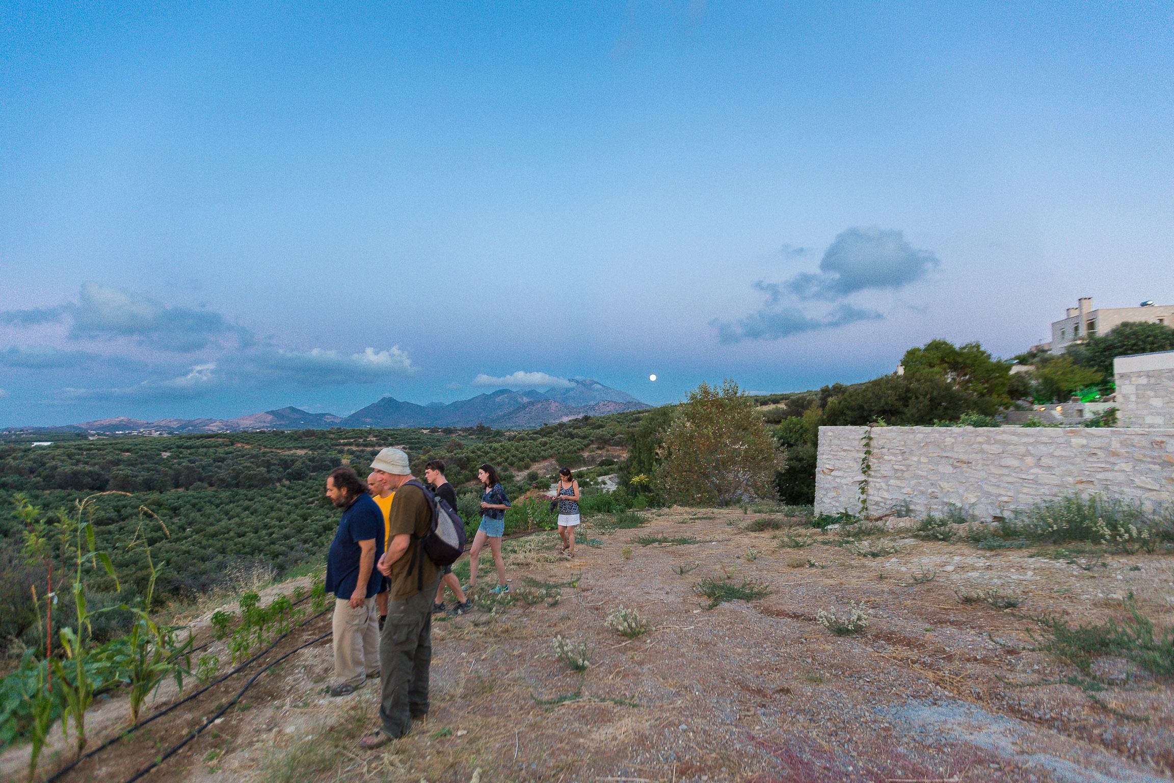 Un groupe de personnes marchant sur un sentier rocailleux, avec un paysage montagneux en arrière-plan.