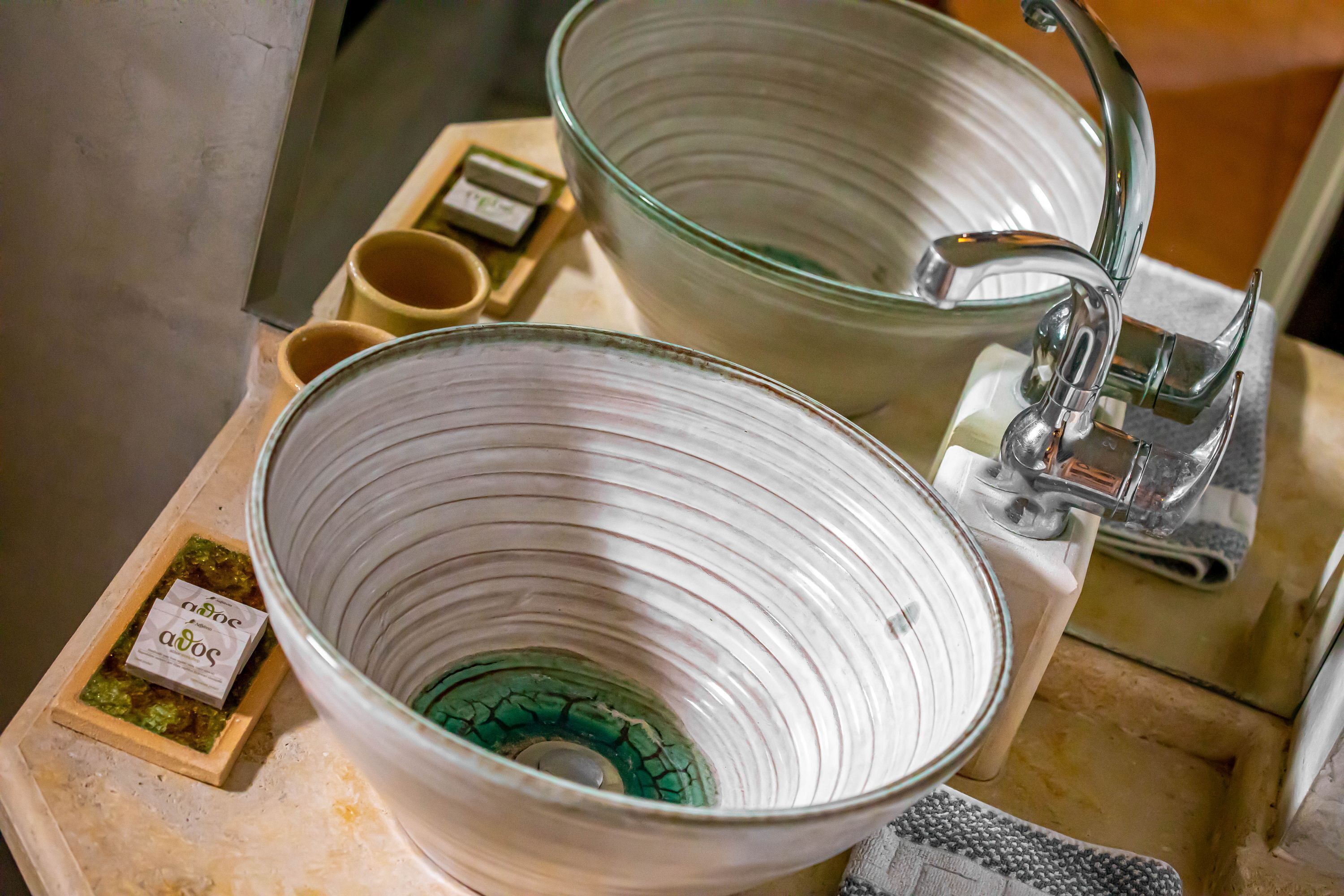 A bathroom sink with a large glass bowl and a faucet. There are two small containers with labels on the counter.