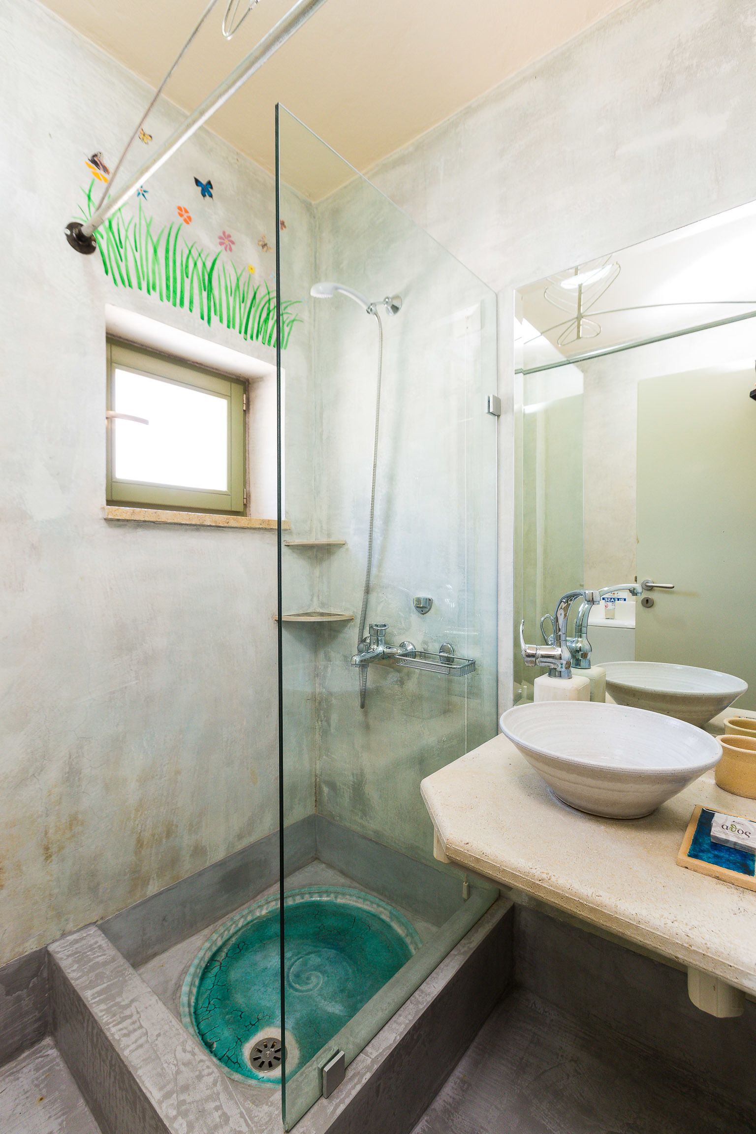 Une salle de bain avec une douche à parois de verre, un lavabo et une fenêtre située au-dessus de la douche.