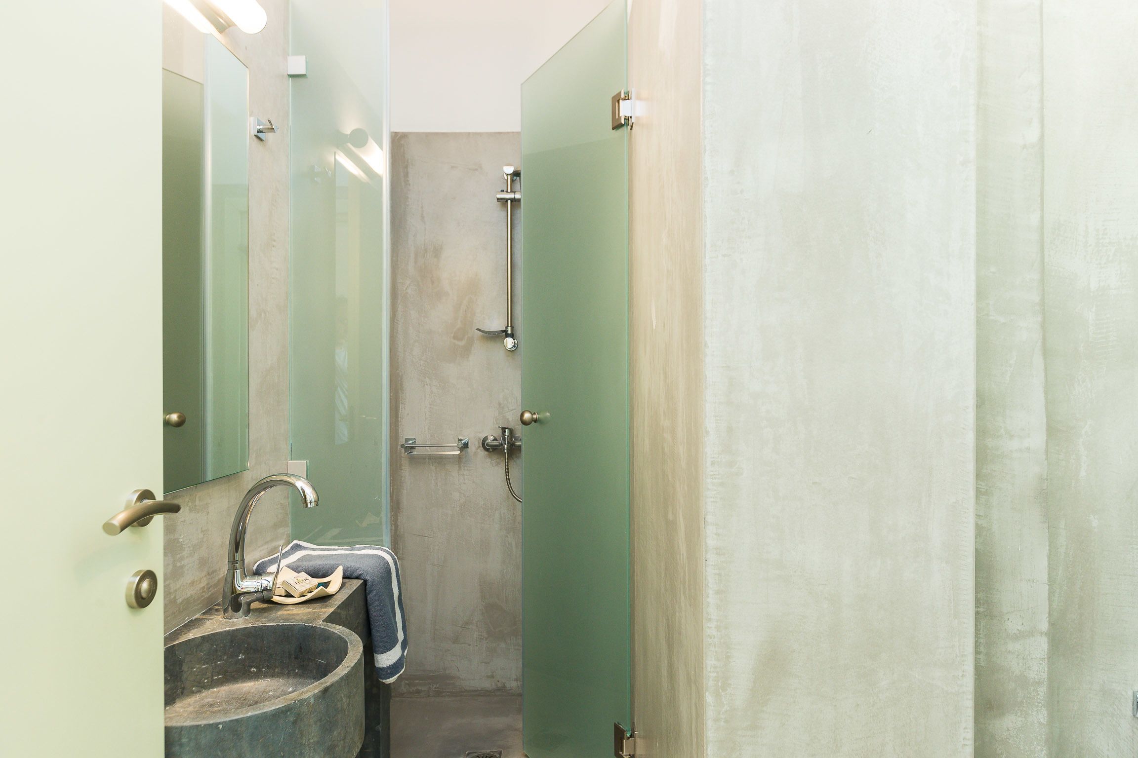 Ein Badezimmer mit einem großen Waschbecken, einem Spiegel und einer Duschkabine.